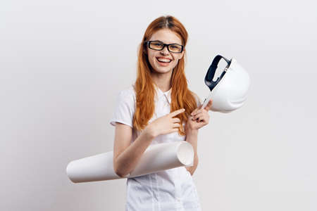 Beautiful young woman engineer on white isolated background holds blueprints.