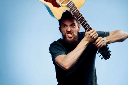 Young guy with a beard on a blue background holds a guitar.の写真素材