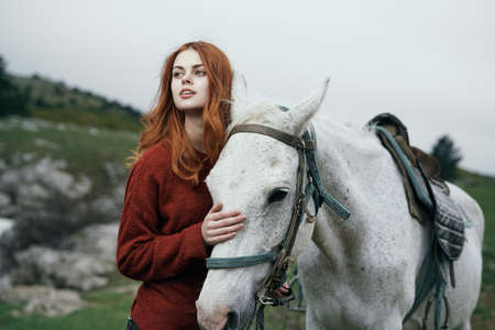 Beautiful young woman walking with her horse in the mountains.の写真素材