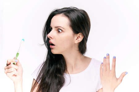 Beautiful young woman on white isolated background holds toothbrush.