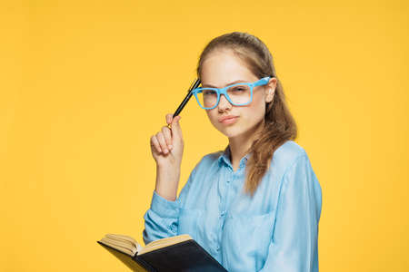 Beautiful young woman in glasses on a yellow background, portrait.の写真素材
