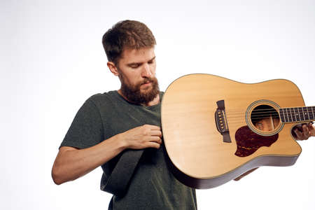Young guy with a beard on a light background holds a guitar.の写真素材