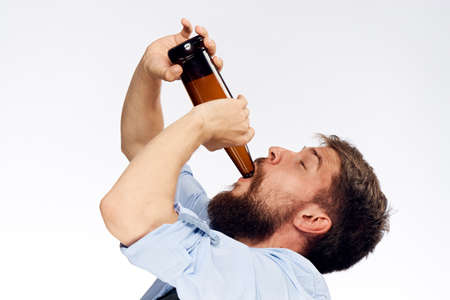 A young guy with a beard on a light background drinks beer.の写真素材