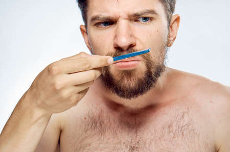 Young guy with a beard on a white isolated background holds a comb.