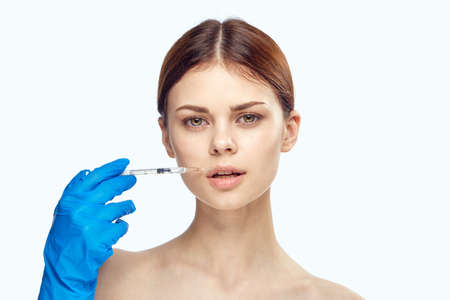 Beautiful young woman on white isolated background holds a syringe, medicine, plastic.