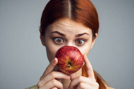 Beautiful young woman on a gray background holding an apple.の写真素材
