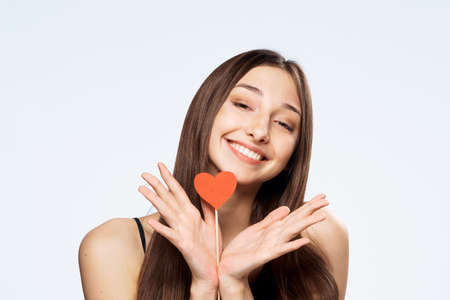 Beautiful young woman on white isolated background holds paper accessories for parties.の写真素材