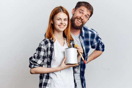 Young beautiful woman and guy with beard on white isolated background, repair, building materials,...
