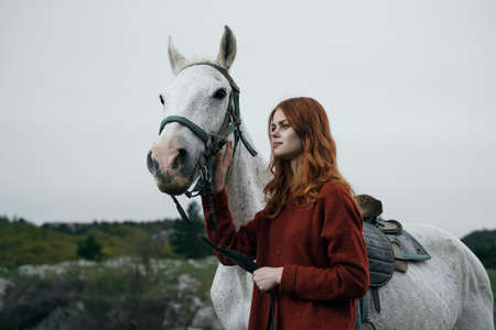 Beautiful young woman in the mountains walking with her horse.の写真素材