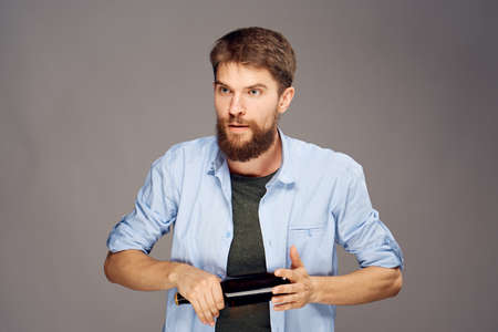 A young guy with a beard on a gray background holds a bottle of beer.の写真素材
