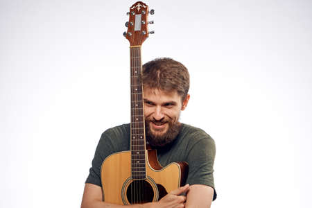 Young guy with a beard on a white isolated background holds a guitar.の写真素材