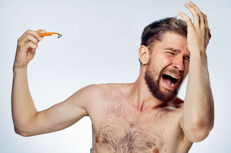 Young guy with a beard on a white isolated background holds a razor.の写真素材