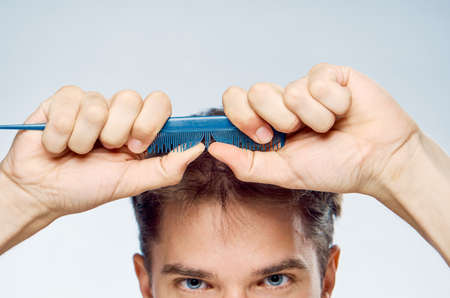 Young guy with a beard on a white isolated background holds a comb.の写真素材