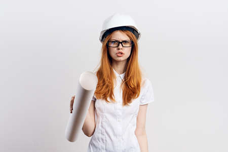 Beautiful young woman on white isolated background holds blueprints, engineer.の写真素材