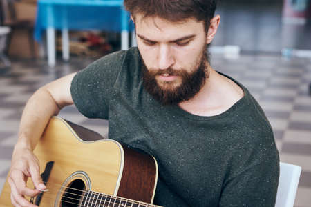 Young guy with a beard playing the guitar.の写真素材
