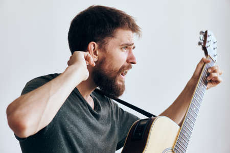 Young guy with a beard on a white isolated background holds a guitar.の写真素材