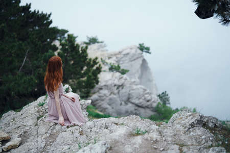 Young beautiful woman on a cliff of a mountain near the sea.の写真素材