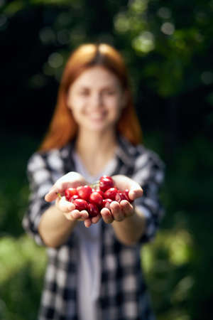Young beautiful woman in summer garden holding berries.の写真素材