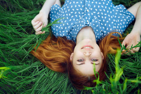 Young beautiful woman lies in the grass in the field, summer.の写真素材