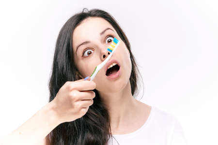 Young beautiful woman on white isolated background holds toothbrush.の写真素材