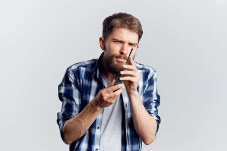 Young guy with a beard on a white isolated background holds a comb.の写真素材