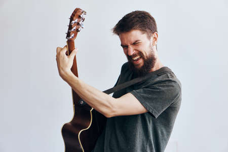 Young guy with a beard on a white isolated background playing a guitar.の写真素材