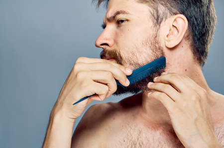 Young guy with a beard on a gray background combing.の写真素材