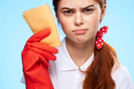 Young beautiful woman on a blue background in rubber gloves, cleaning, housework.の写真素材