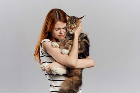 Young beautiful woman on a light background holds a cat.の写真素材