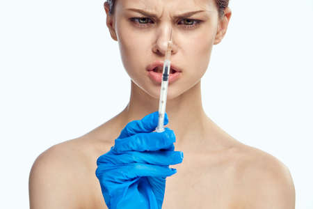 Young beautiful woman on white isolated background holds a syringe, plastic surgery, medicine.の写真素材