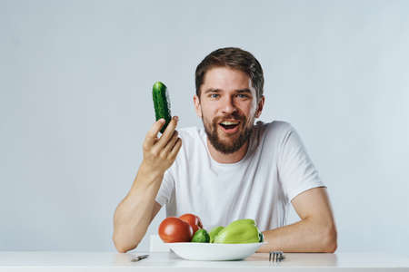 Young guy with beard on white isolated background, vegetables, vegan, healthy eating right.の写真素材