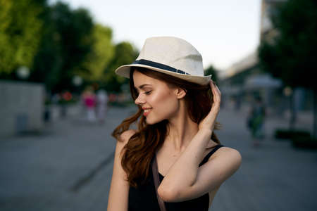 Young beautiful woman in a hat walking along a street in the city.の写真素材