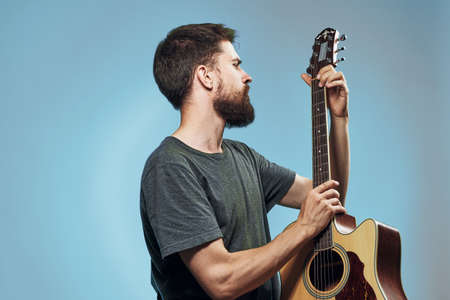 A man with a beard on a blue background holds a guitar, music, musical instruments, play, strings.の写真素材