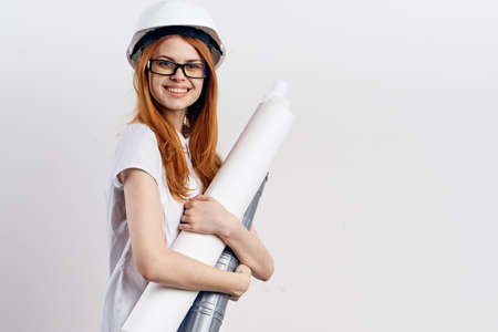 Young beautiful woman on white isolated background holds blueprints, designer, engineer.の写真素材