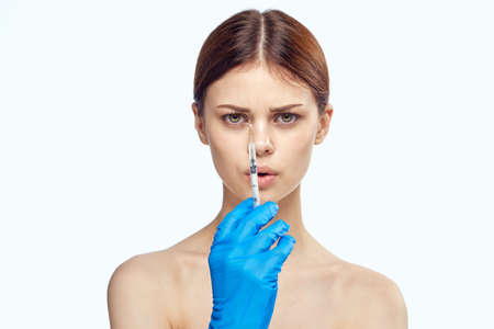 Young beautiful woman on white isolated background holds a syringe, plastic surgery, medicine.の写真素材