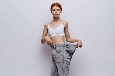 Young beautiful woman on a light background, losing weight, sports, fitness, progress, success.の写真素材
