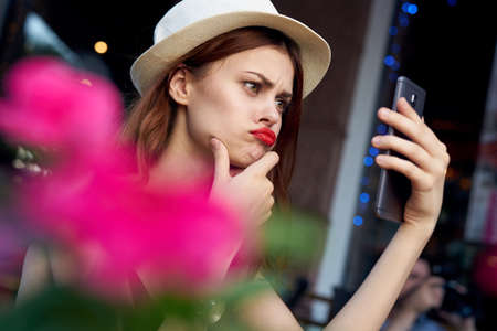 Young beautiful woman doing selfie sitting in a cafe on the street.の写真素材