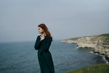 Young beautiful woman on a cliff of a mountain near the sea.