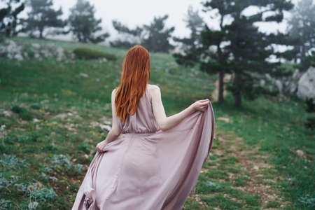 Beautiful young woman in a long dress walking in the mountains outdoors.の写真素材