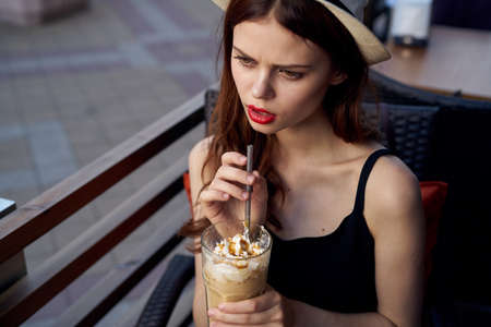Beautiful young woman drinks coffee in a cafe on a summer street.の写真素材