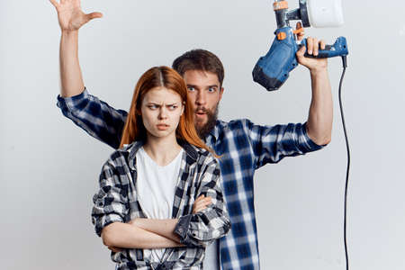 Beautiful young woman and man with a beard on a light background, repair, construction tools.の写真素材