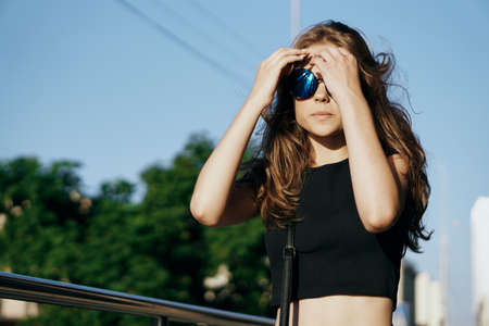 Beautiful young woman is walking along the street in the city in summer.