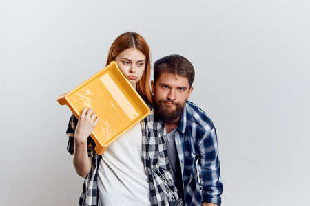 Man with a beard on a light background and a beautiful young woman holding construction tools for repair.の写真素材