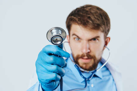 Man with a beard on a light background holds medical instruments, doctor, medicine.の写真素材