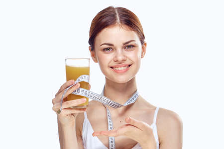 Young beautiful woman on white isolated background holds a glass of freshly squeezed juice, diet, healthy food.の写真素材