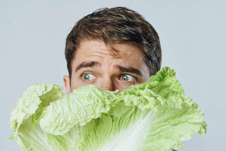 Man with a beard on a light background holds a salad, vegetables, a diet. Vegetarian, vegetarianism.の写真素材