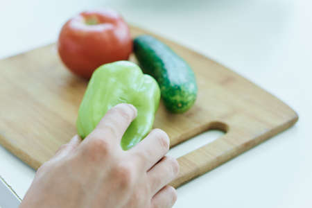 Vegetables lie on a cutting board on a table.