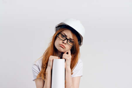 Young beautiful female engineer on white isolated background holds blueprints, construction, designer.の写真素材