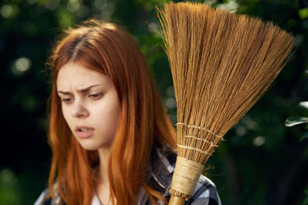 Young beautiful woman running in the garden in summer, gardener, broom.の写真素材