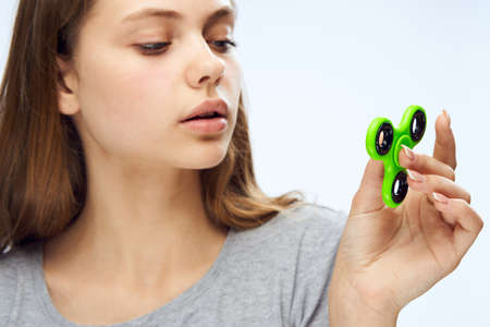 Young beautiful woman on white isolated background holds a fidget spinner.